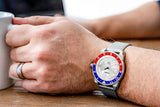 Aquacy Mesh Bracelet Watch Red Blue And Silver On Wrist Holding Cup