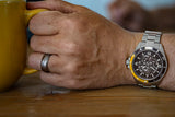 Aquacy Automatic Skeleton Watch Black And Yellow On Wrist Holding Cup